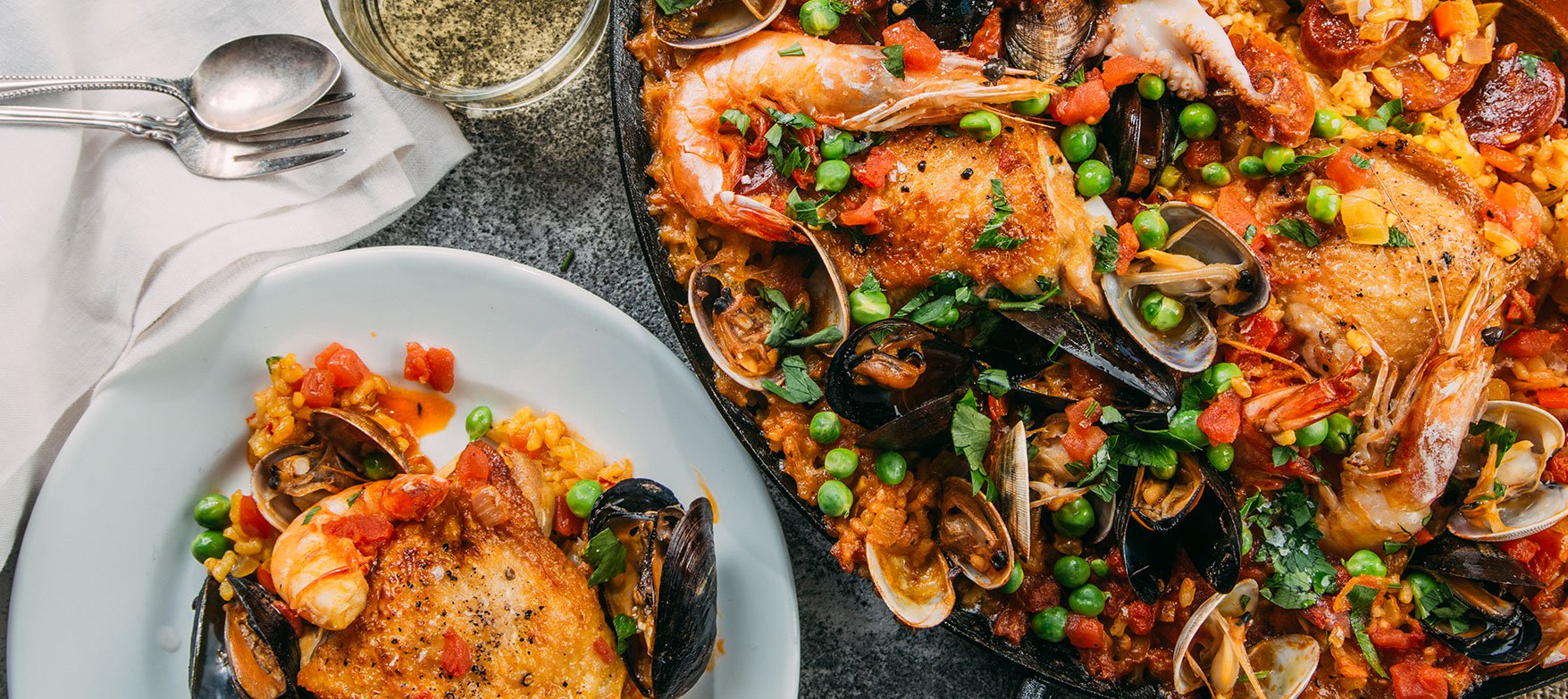 Image of Tuttorosso Tomatoes Paella recipe in a paella pan with a plated serving of rice, chicken and seafood