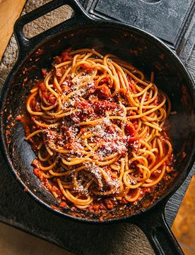 Image of Tuttorosso Tomatoes Recipe Bucatini Amatriciana in an iron skillet pasta with tomato sauce