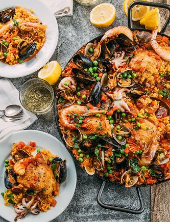 Image of paella with plated servings includes seafood, chicken and Tuttorosso Tomatoes