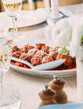 Image of a dinner table with a platter of meatballs and red tomato sauce